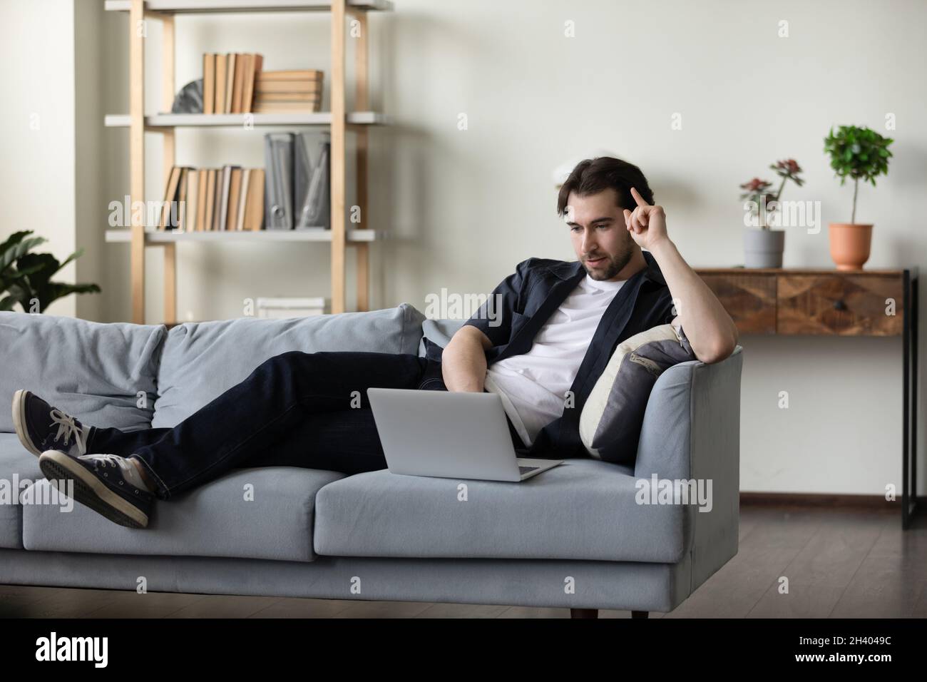 Happy relaxed young man using laptop at home. Stock Photo