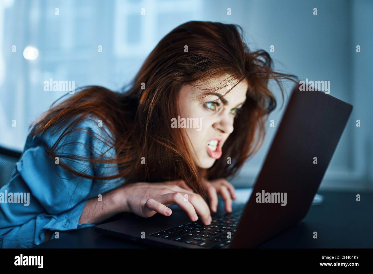 emotional woman in front of laptop at night work disorder Stock Photo