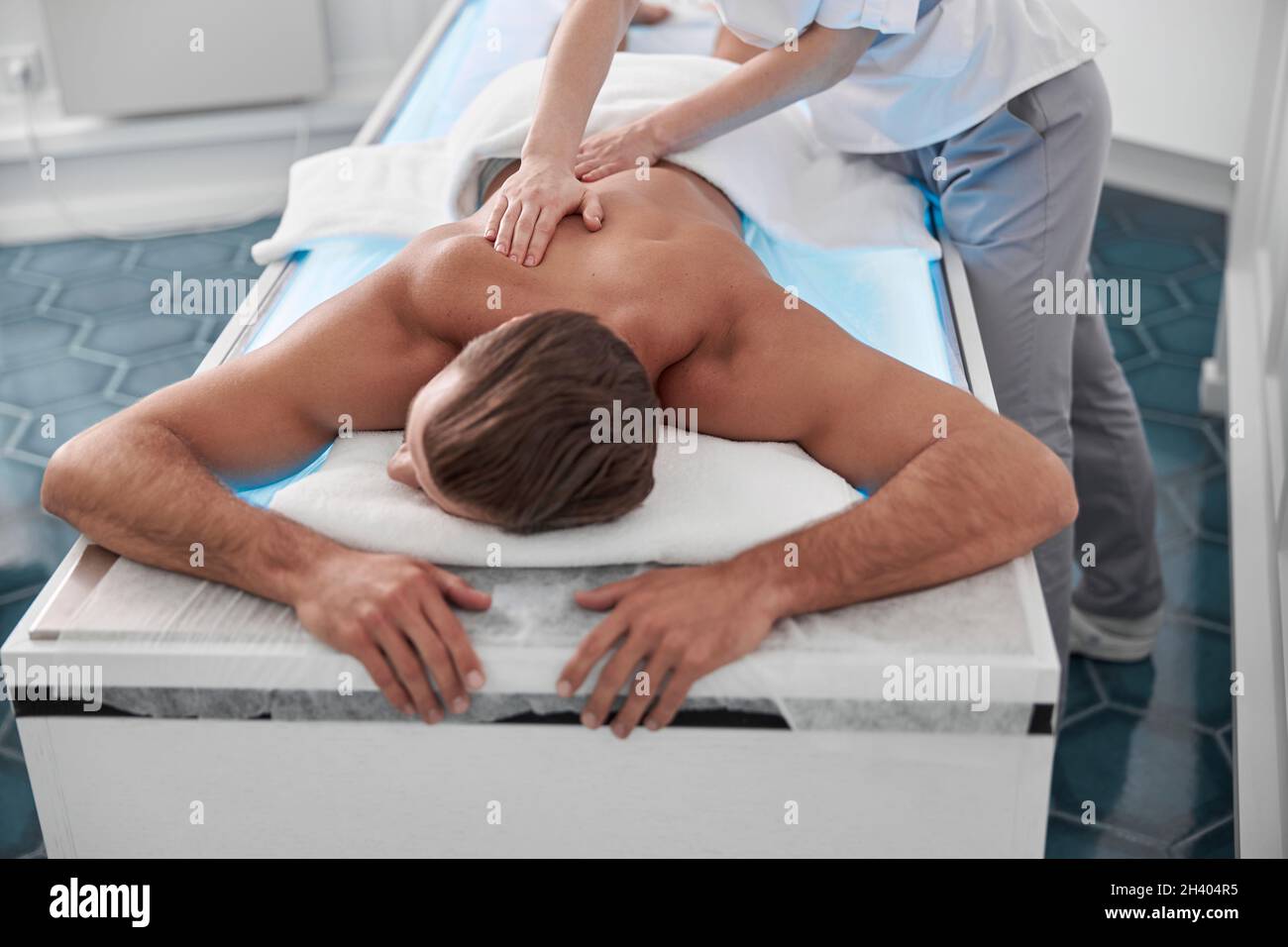 Man lies on comfortable couch while chiropractic does back massage to him in hospital Stock Photo