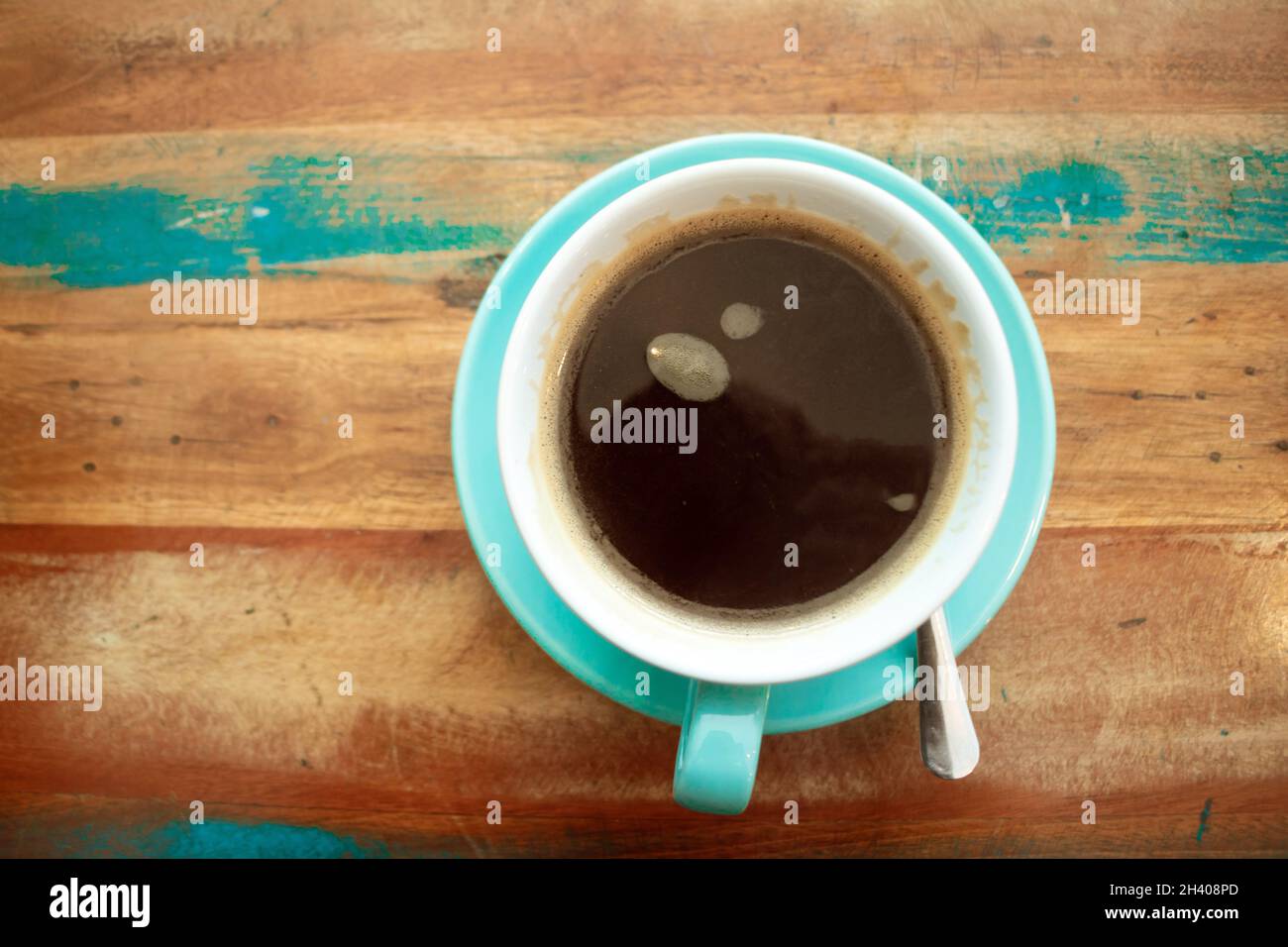 flat lay top view of cup of black coffee on distressed painted table top & saucer Stock Photo