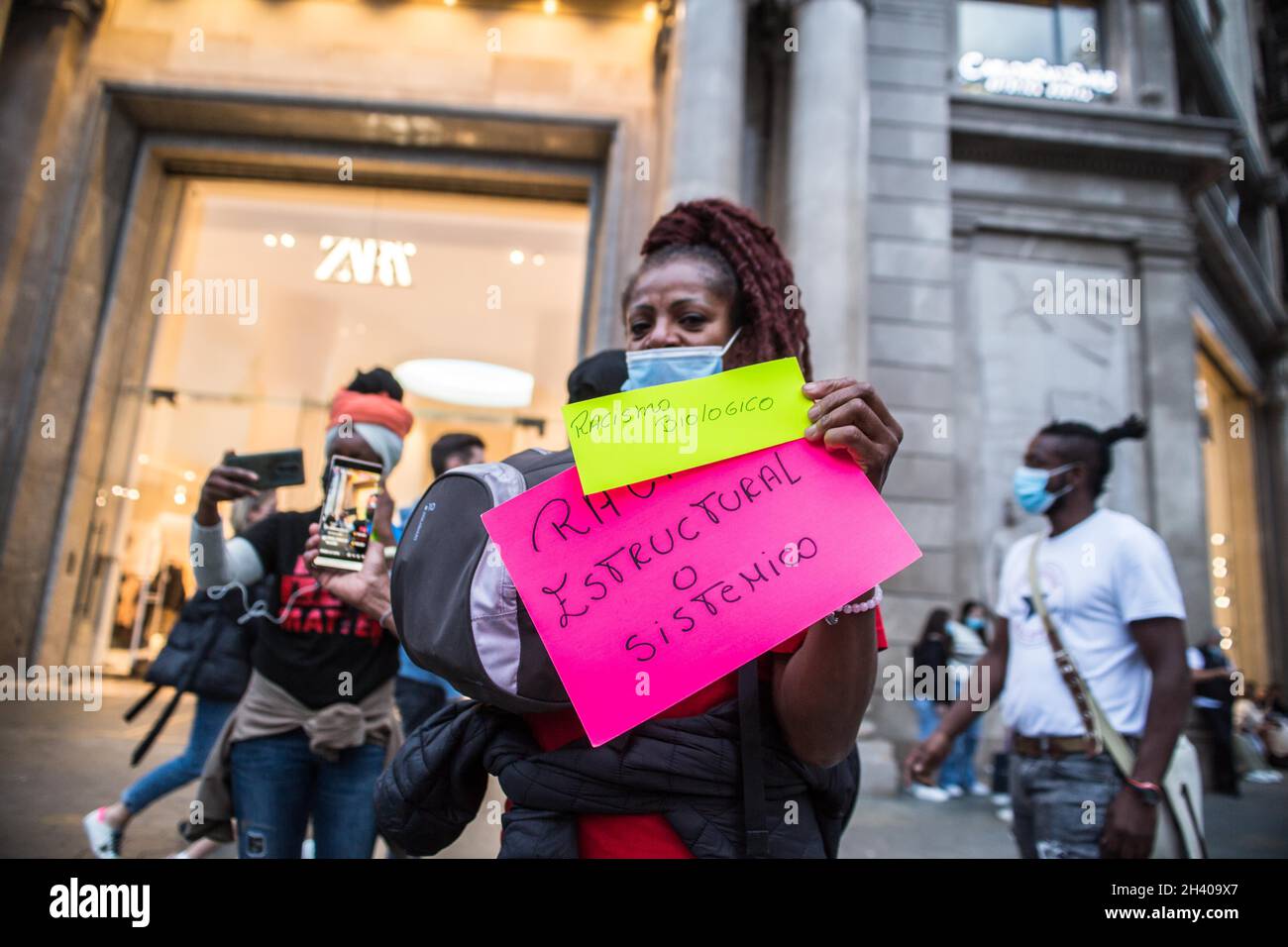 Barcelona, Catalonia, Spain. 29th Oct, 2021. Protester is seen at the door of a clothing store, Zara with banners that say, biological racism and structural or systematic racism.A group of Brazilian activists in Barcelona has held a demonstration inside and outside the main Spanish clothing store, Zara in Barcelona, due to various cases in the last month, in Brazil, in which black people were the victim of racist attacks by the stores Zara which led to a protocol investigation. The investigations affirm that the company has a ''code of conduct'' to identify when people who are not considere Stock Photo