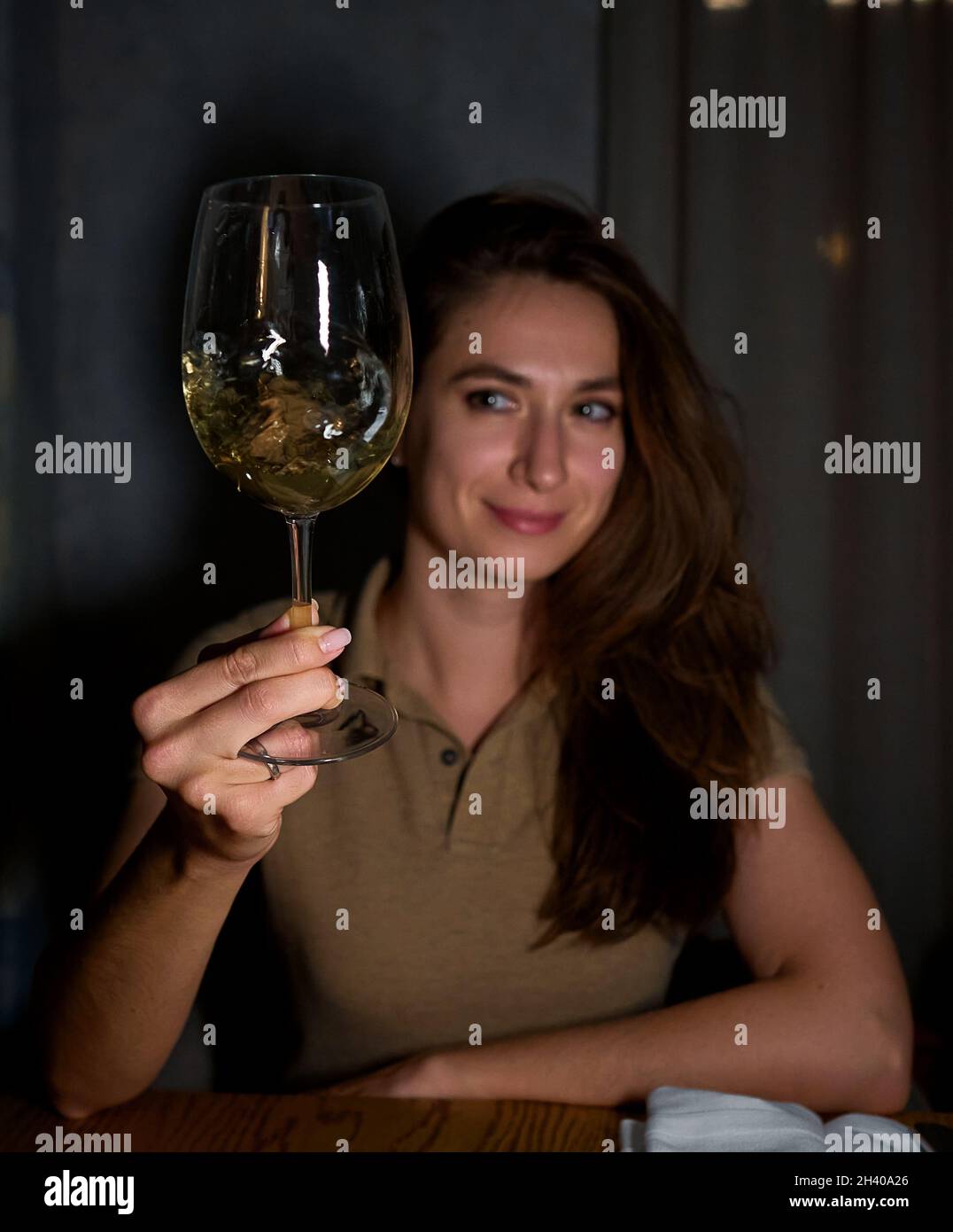 a girl in a white sweater holds a glass of sparkling wine on her outstretched hand Stock Photo
