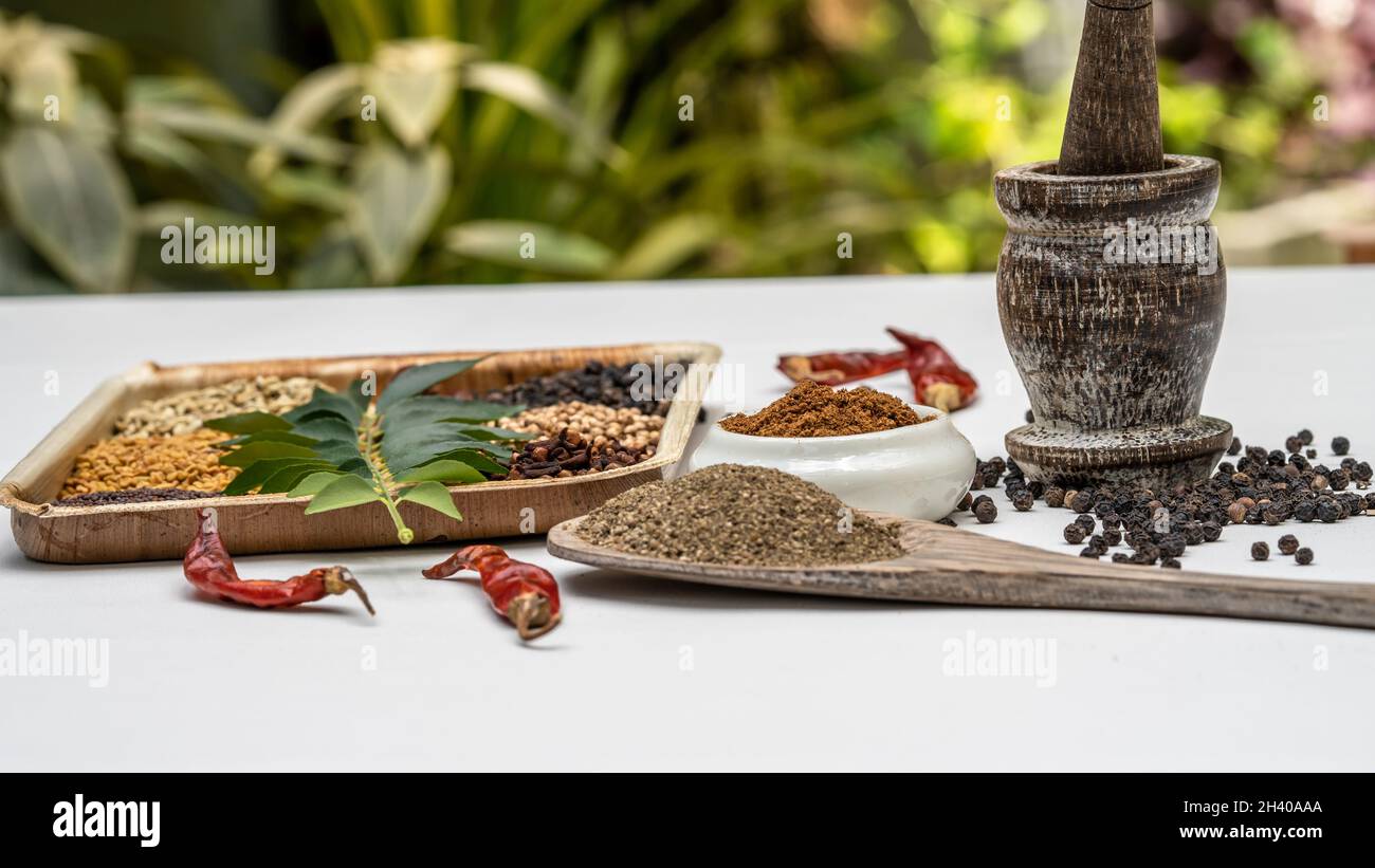 Black pepper seeds and powder placed in a wooden mortar were placed on a white background. Stock Photo
