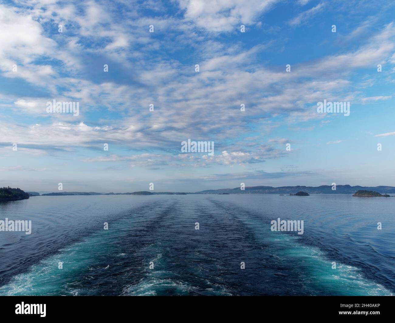 Looking astern from a Vessel moving through Bergen Fjord with its wake disappearing into the distance as it travels towards its destination. Stock Photo
