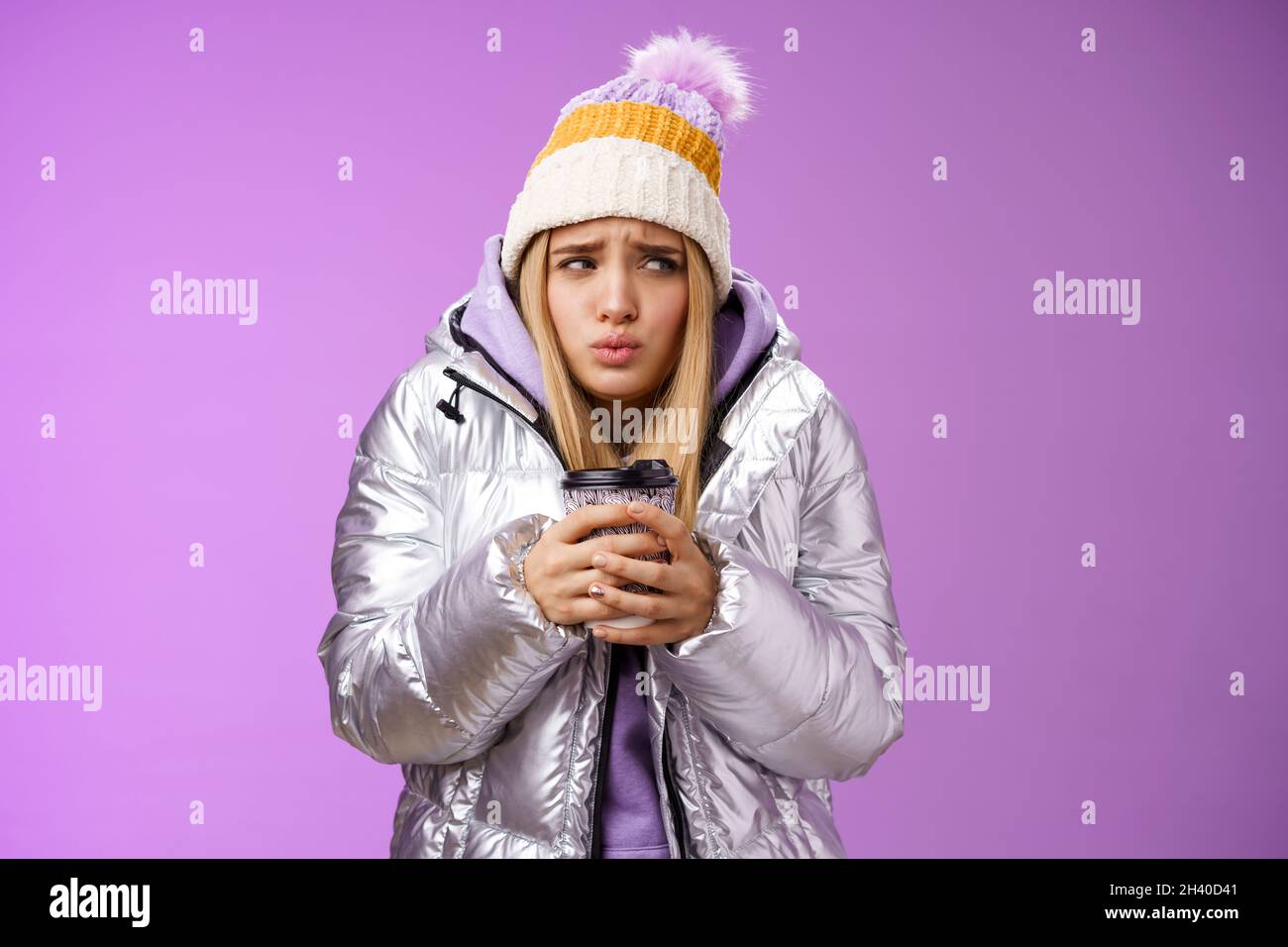 Trembling uncomfortable cute pouting young blond girl feel freezing cold winter snowy weather outside shaking low temperature ho Stock Photo