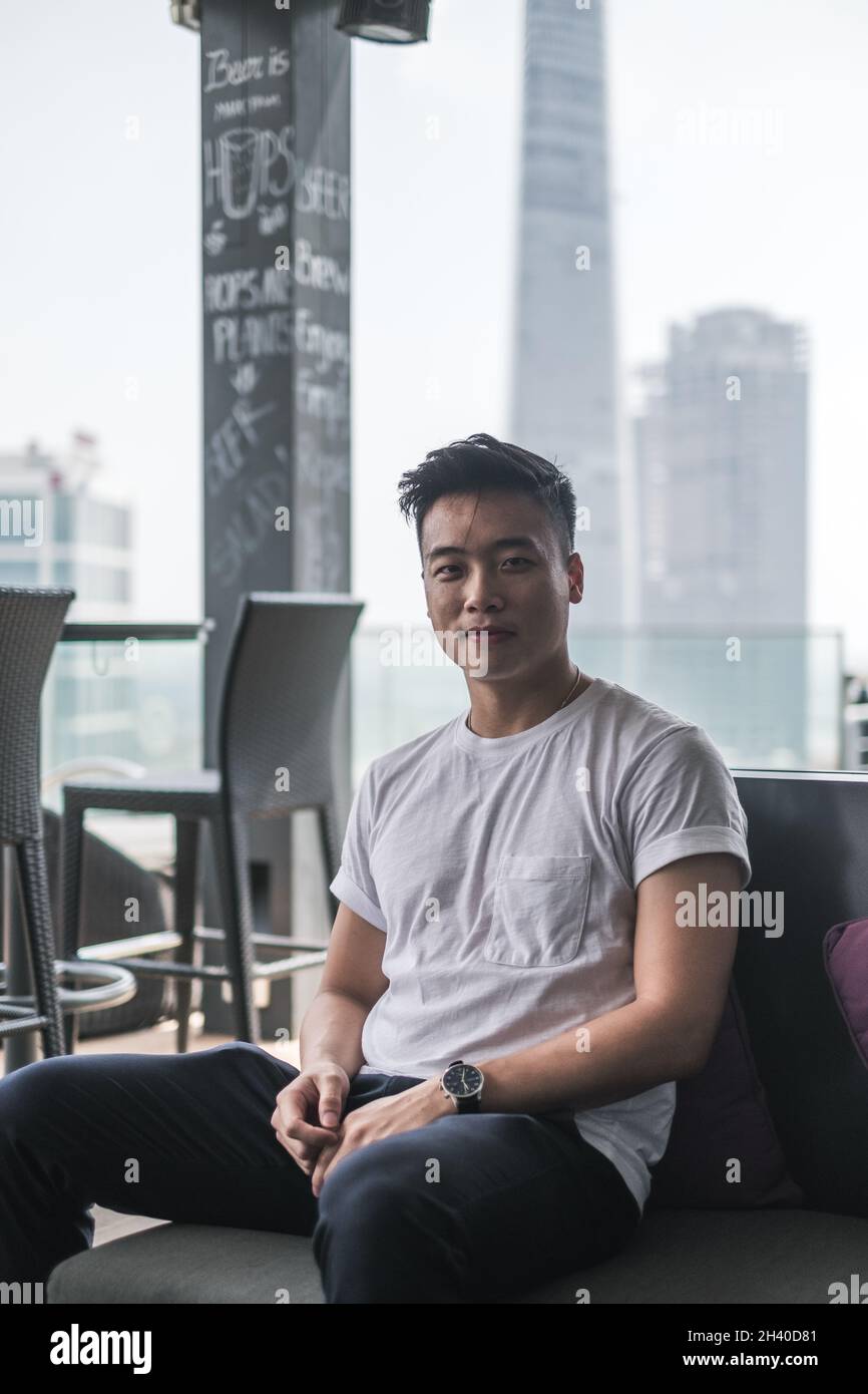 Handsome young Asian man sitting on the rooftop. Chinese guy, millennials life, lifestyle in the big city, Modern Asia Stock Photo