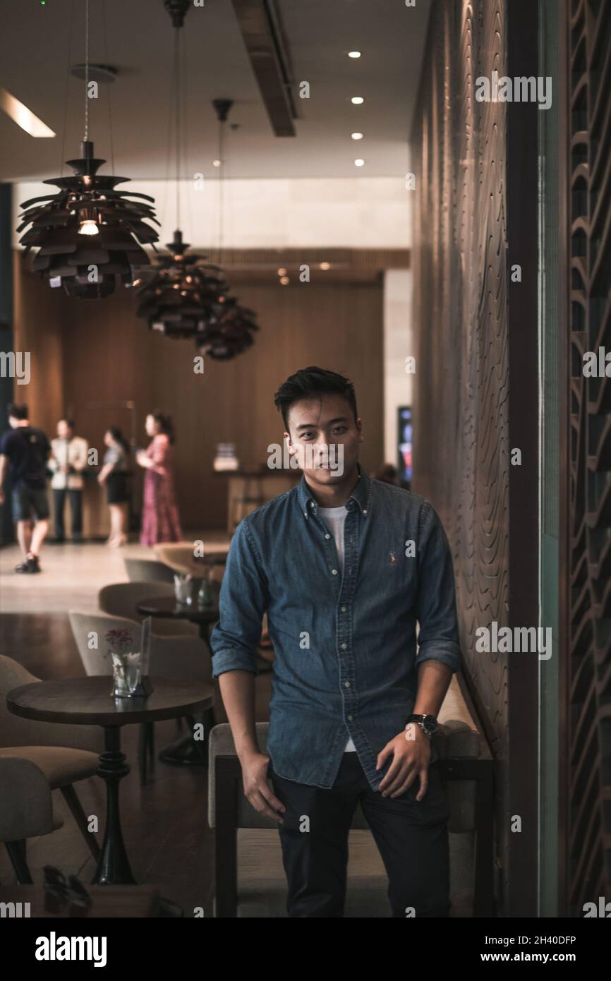 Asian young handsome man standing in coffee shop and smiling. Chinese guy, millennials life, lifestyle in the big city, Modern Asia, coffee break Stock Photo