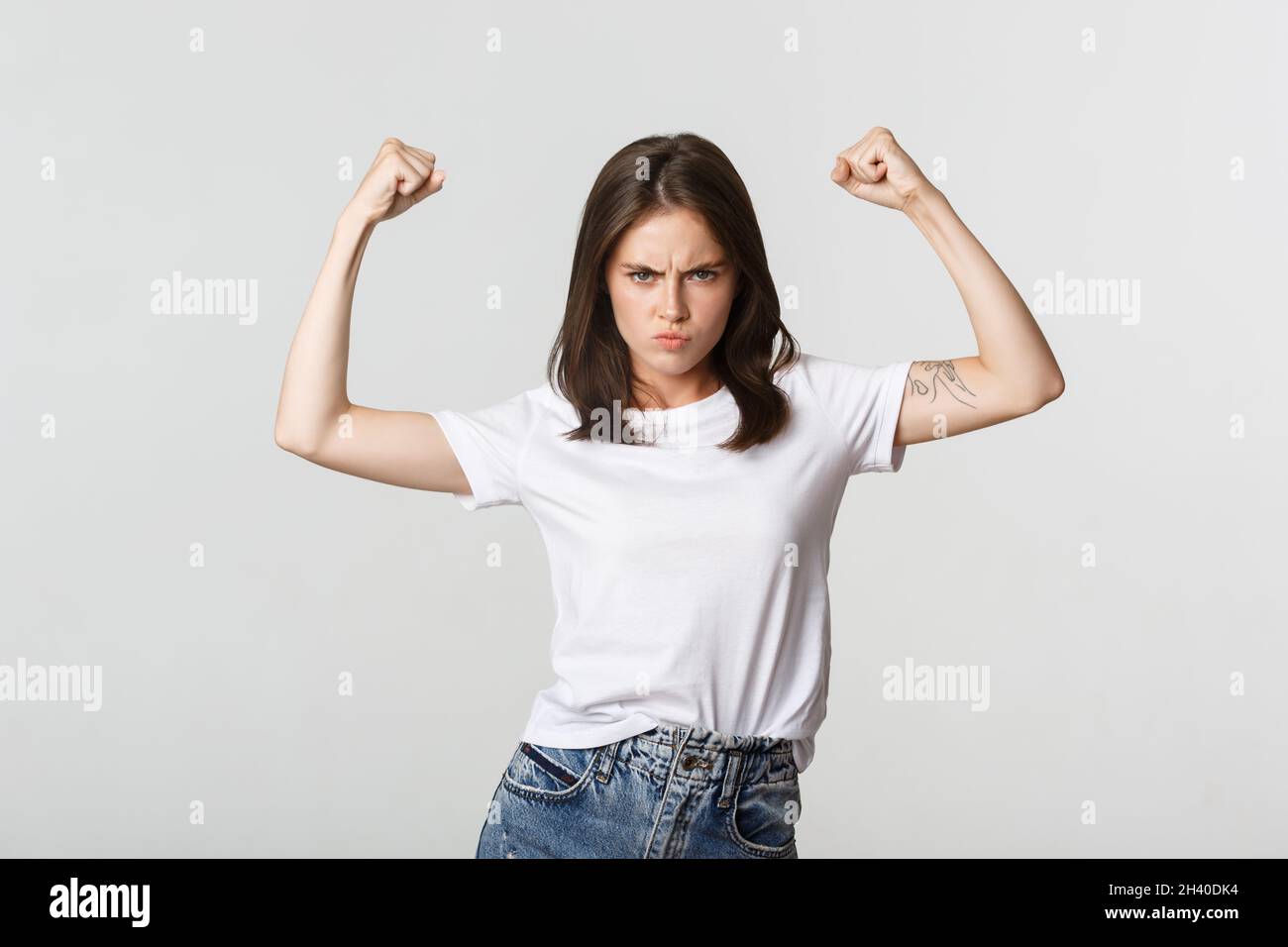 Serious-looking confident brunette girl flex biceps, showing strengths Stock Photo