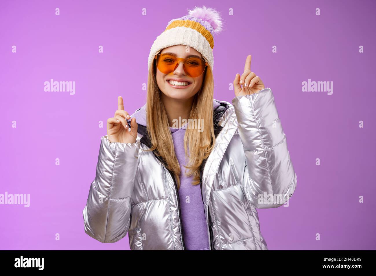 Joyful energized entertained cute blond woman having fun enjoy vacation snowy mountain trip wearing sunglasses silver jacket win Stock Photo