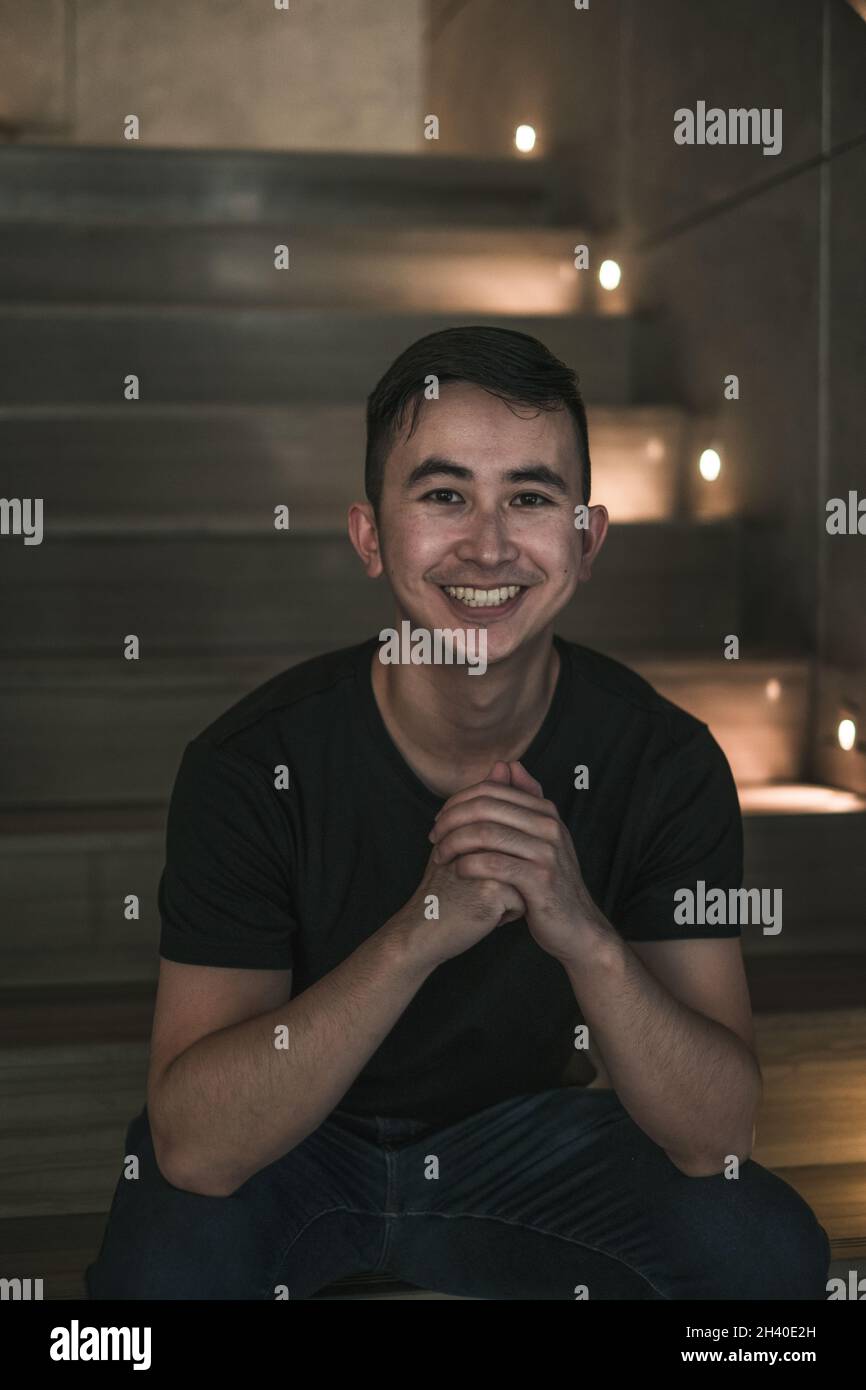 Asian young handsome man sitting on the stairs shop and smiling ...