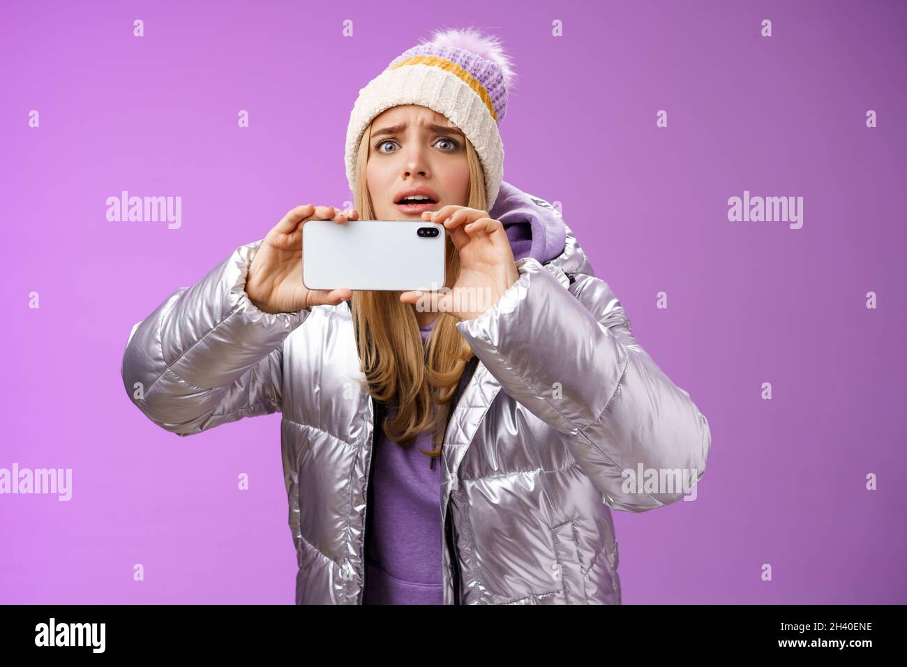 Intense worried blond girl holding mobile phone horizontal recording video capture moment share friends internet blog using smar Stock Photo