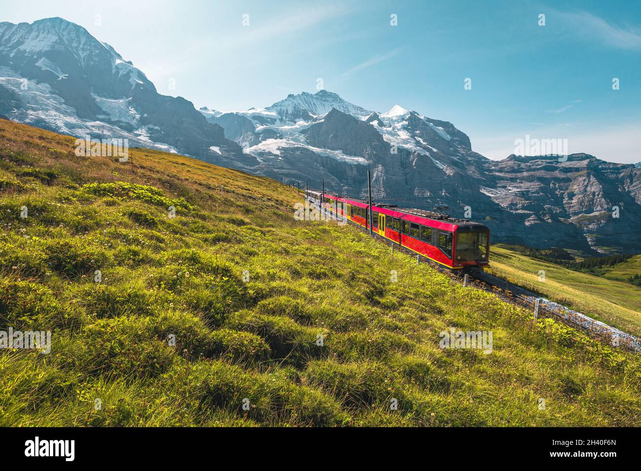 Cogwheel railway with modern electric red tourist train. Snowy Jungfrau mountains and red passenger train on the Jungfraujoch, Kleine Scheidegg, Grind Stock Photo