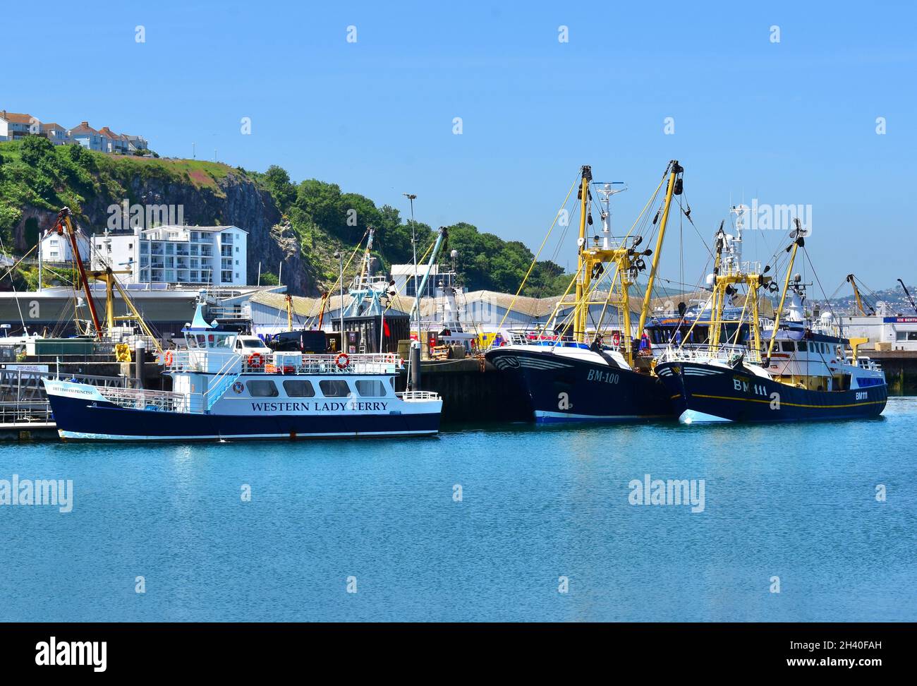 The Western Lady ferry boat provides a holiday service between Brixham and Torquay. Trawler fishing boats moored at the same quay. Stock Photo