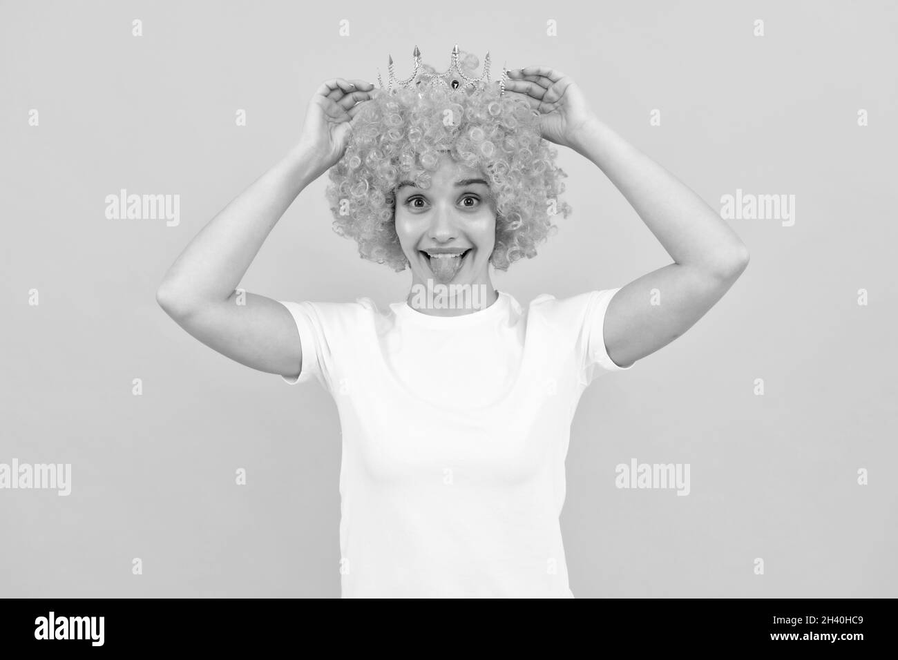 happy egoistic funny girl with fancy look wearing orange hair wig and princess crown, winner Stock Photo