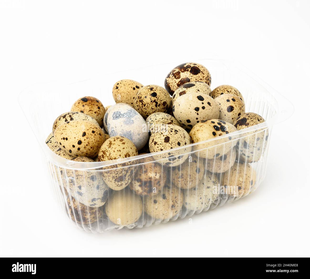 A bunch of raw quail eggs in a plastic transparent container on a white background, diet food Stock Photo