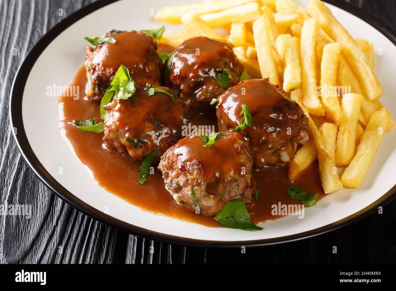 Boulets liegeois Liege Meatballs in apple sauce and French fries closeup in the plate on the table. Horizontal Stock Photo