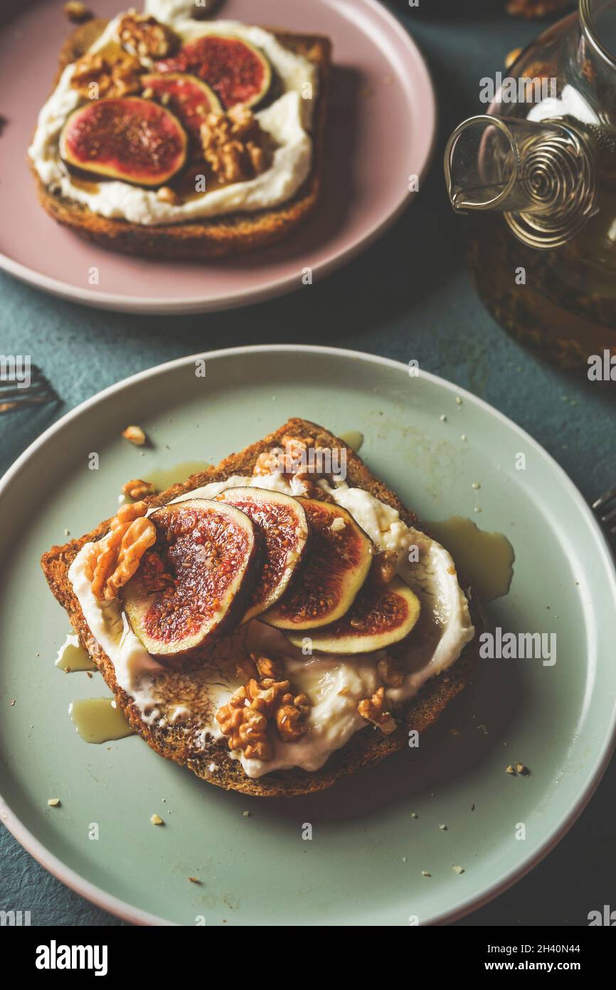Close up of French toast with whipped cream and sliced figs, walnuts and maple syrup on grey kitchen table. Sweet breakfast at home. Top view. Stock Photo