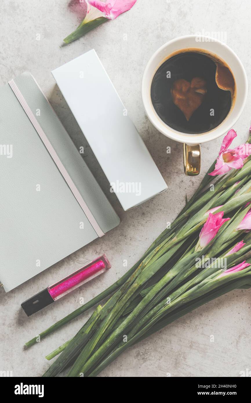 Freelancer breakfast with coffee, flowers, notepad and pink lip gloss