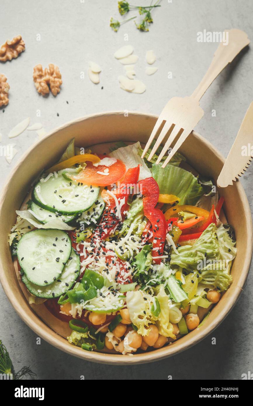 Colorful salad with vegetables in plastic free delivery food container: cucumber, pepper, salad, chickpeas and nuts. Sustainable lifestyle with health Stock Photo