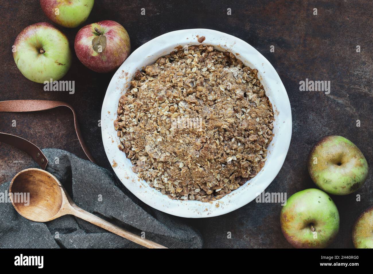 Fresh hot homemade apple crisp or crumble with crunchy streusel topping topped over rustic background with wooden spoon. Top view. Stock Photo