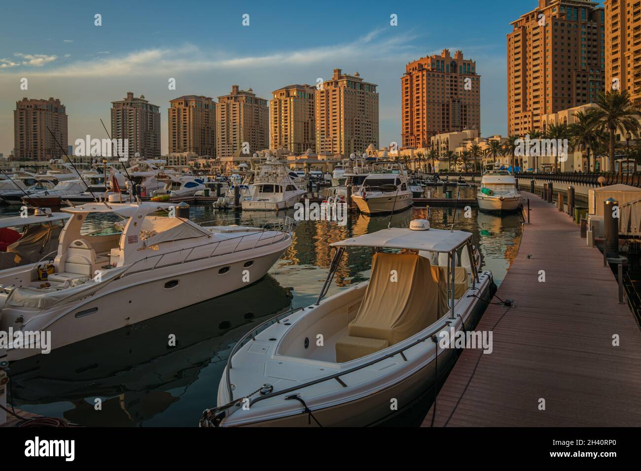 Porto Arabia Marina in The pearl Doha, Qatar sunset  shot showing luxurious yachts docked at the marina with  residential buildings in background. Stock Photo