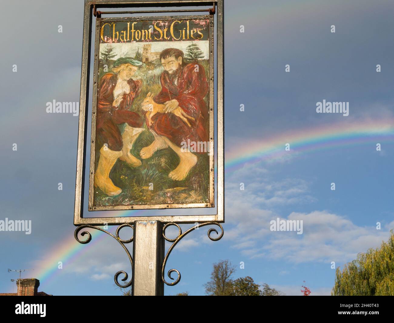 Village sign of Chalfont St Giles Buckinghamshire England UK one of the Chalfonts villages rainbow in sky behind sign Stock Photo