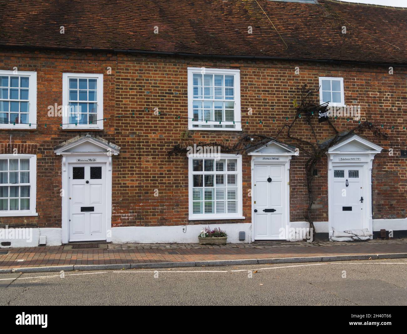 Row of red bricked cottages with white doors including Bakehouse dating to 1749 Chalfont St Giles Buckinghamshire England UK Stock Photo