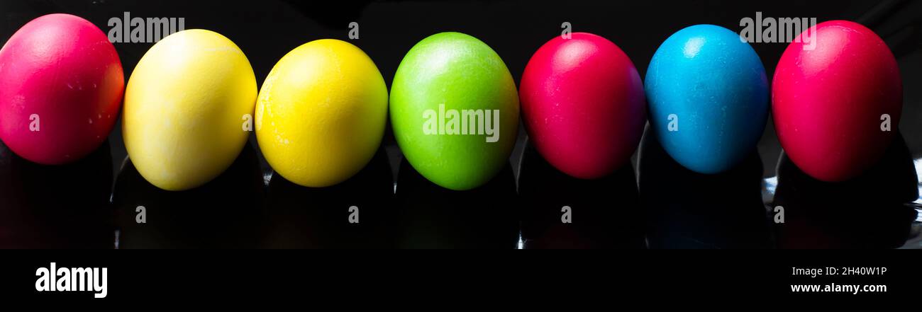 Easter backgrounds. Multicolored Easter eggs on a black background. Banner. Stock Photo
