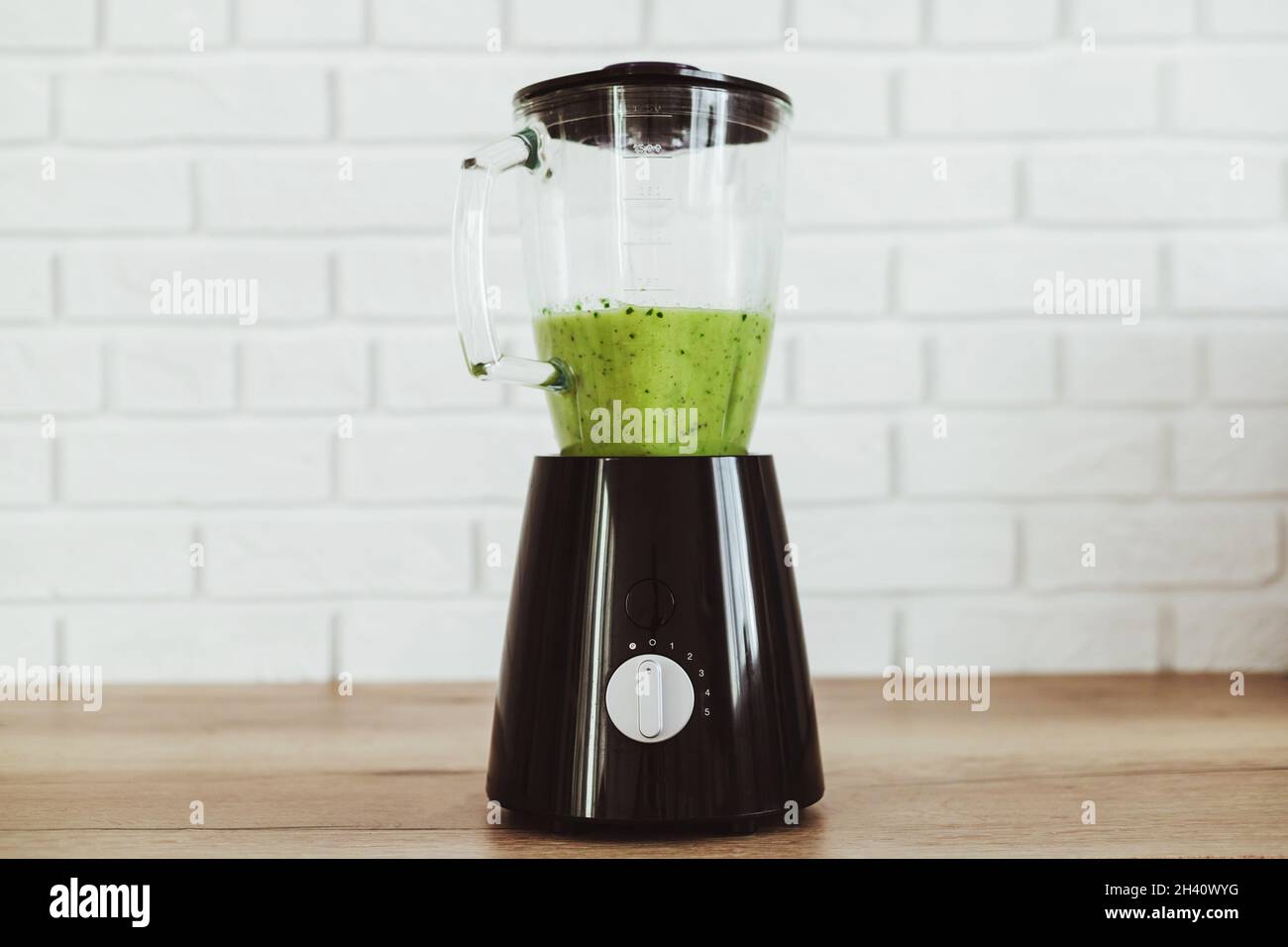 Stationary blender with healthy green smoothie on table in kitchen Stock Photo