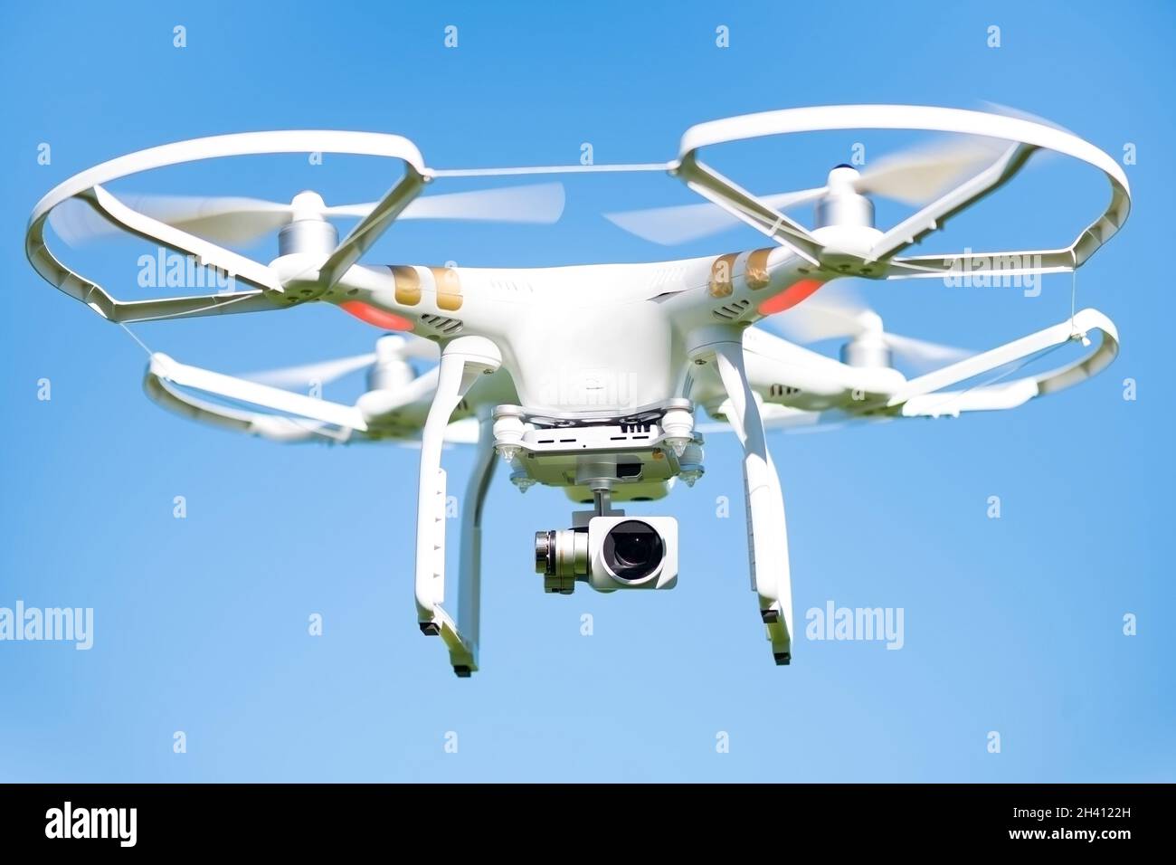 White drone flying high in the air, these unmanned aerial vehicles are intended for recreational and commercial aerial cinematography and photography Stock Photo