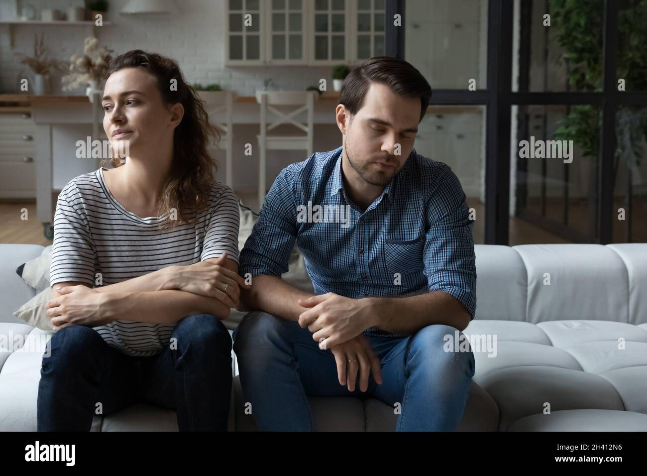 Depressed unhappy young couple sitting on sofa. Stock Photo