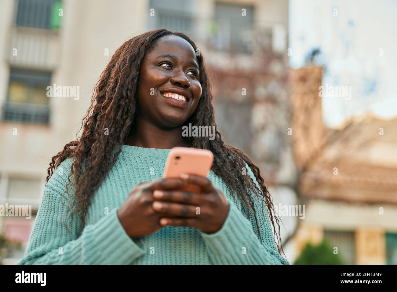 Young african woman smiling happy using smartphone at the city Stock ...