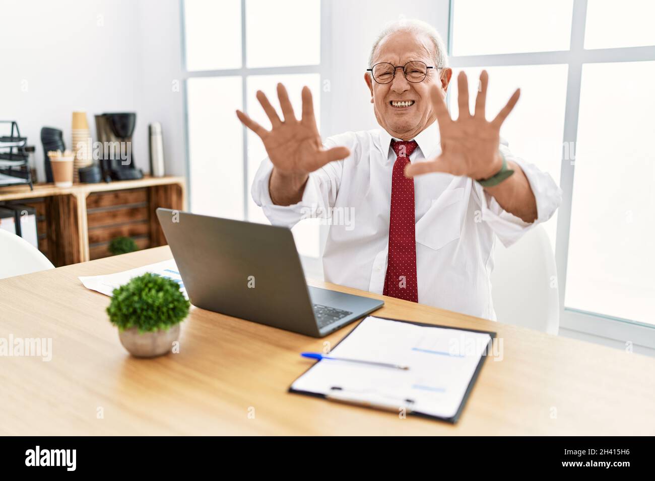 Senior man working at the office using computer laptop doing stop gesture with hands palms, angry and frustration expression Stock Photo