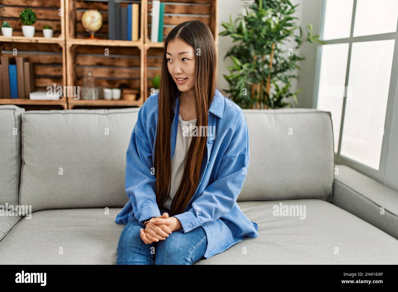 Young chinese girl smiling happy sitting on the sofa at home Stock ...