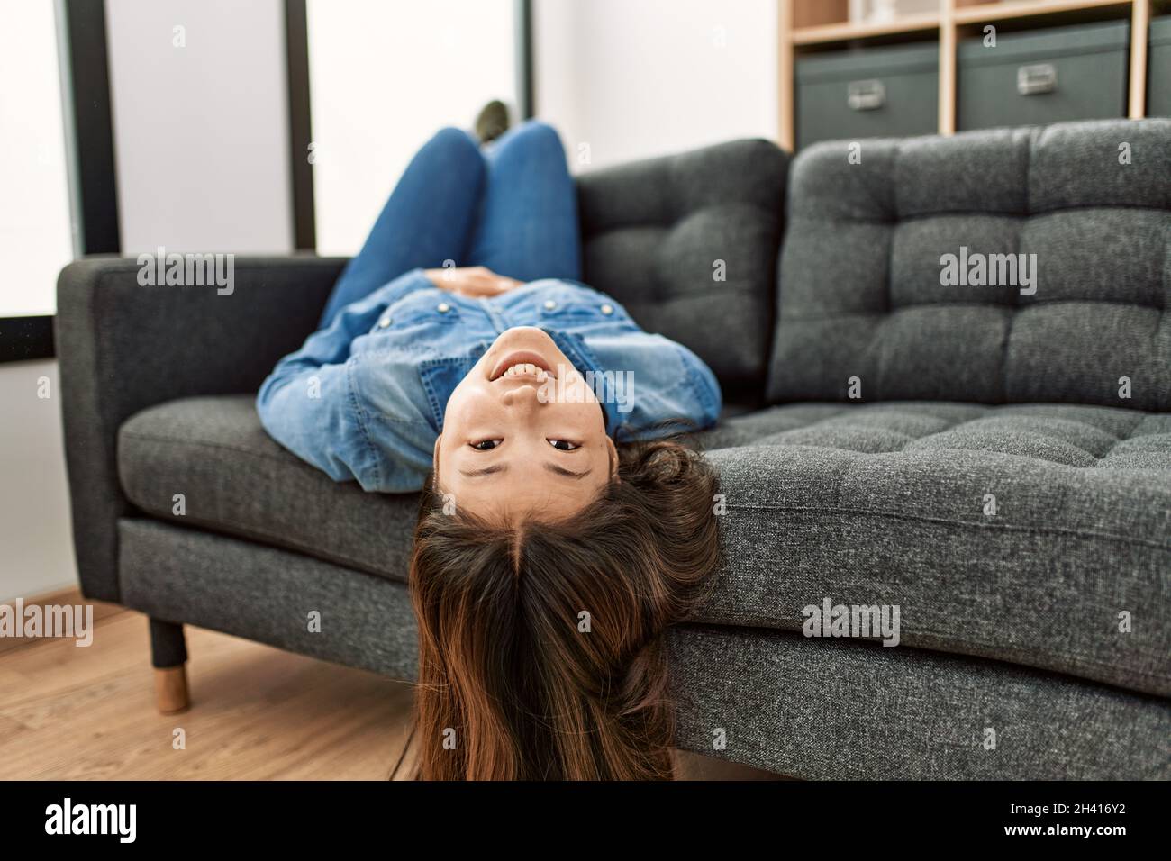 Young chinese girl smiling happy lying on the sofa at home Stock Photo ...