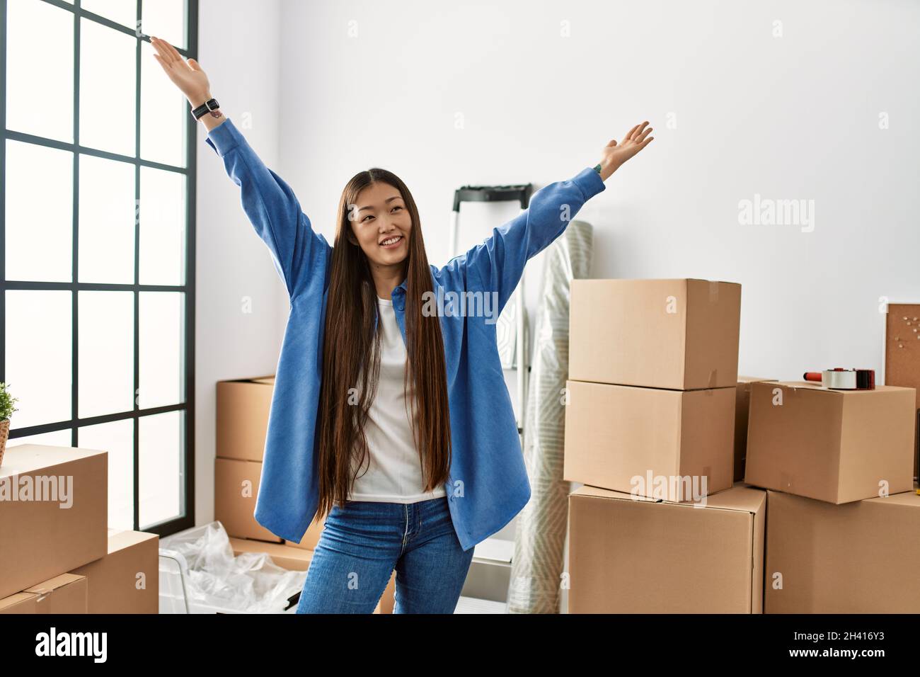 Young chinese girl smiling happy and confident with hands raised up at ...