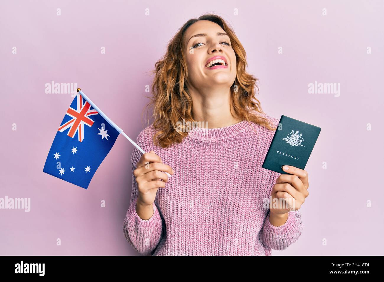 Young caucasian woman holding australian flag and passport smiling and  laughing hard out loud because funny crazy joke Stock Photo - Alamy