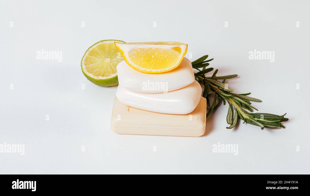 Natural organic soap bars stack with lemon, rosemary and lime on white background, close-up Stock Photo