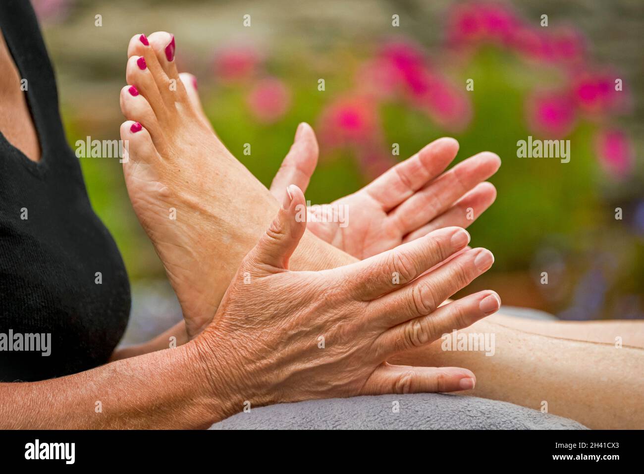 Horizontal close up of a reflexologist giving a foot treatment outside in the fresh air. Stock Photo