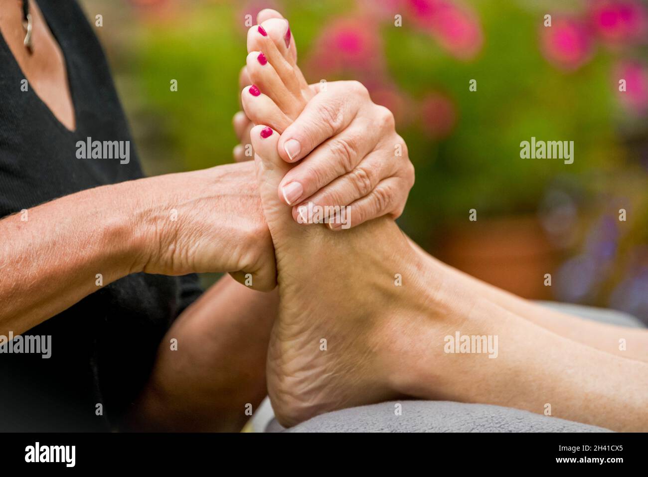 Horizontal close up of a reflexologist applying pressure to the sole of a foot during a treatment. Stock Photo