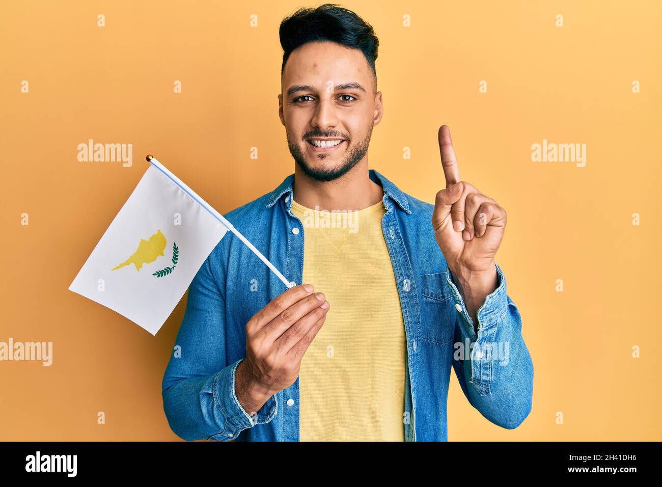 Young Arab Man Holding Cyprus Flag Smiling With An Idea Or Question Pointing Finger With Happy Face Number One Stock Photo Alamy