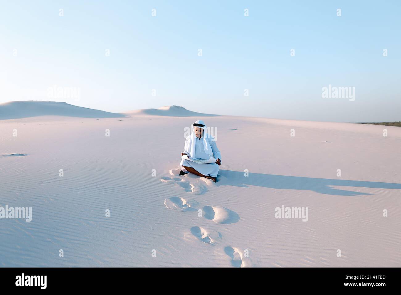 Serious young Arab businessman considering construction plan, standing among wide desert on hot summer day. Stock Photo
