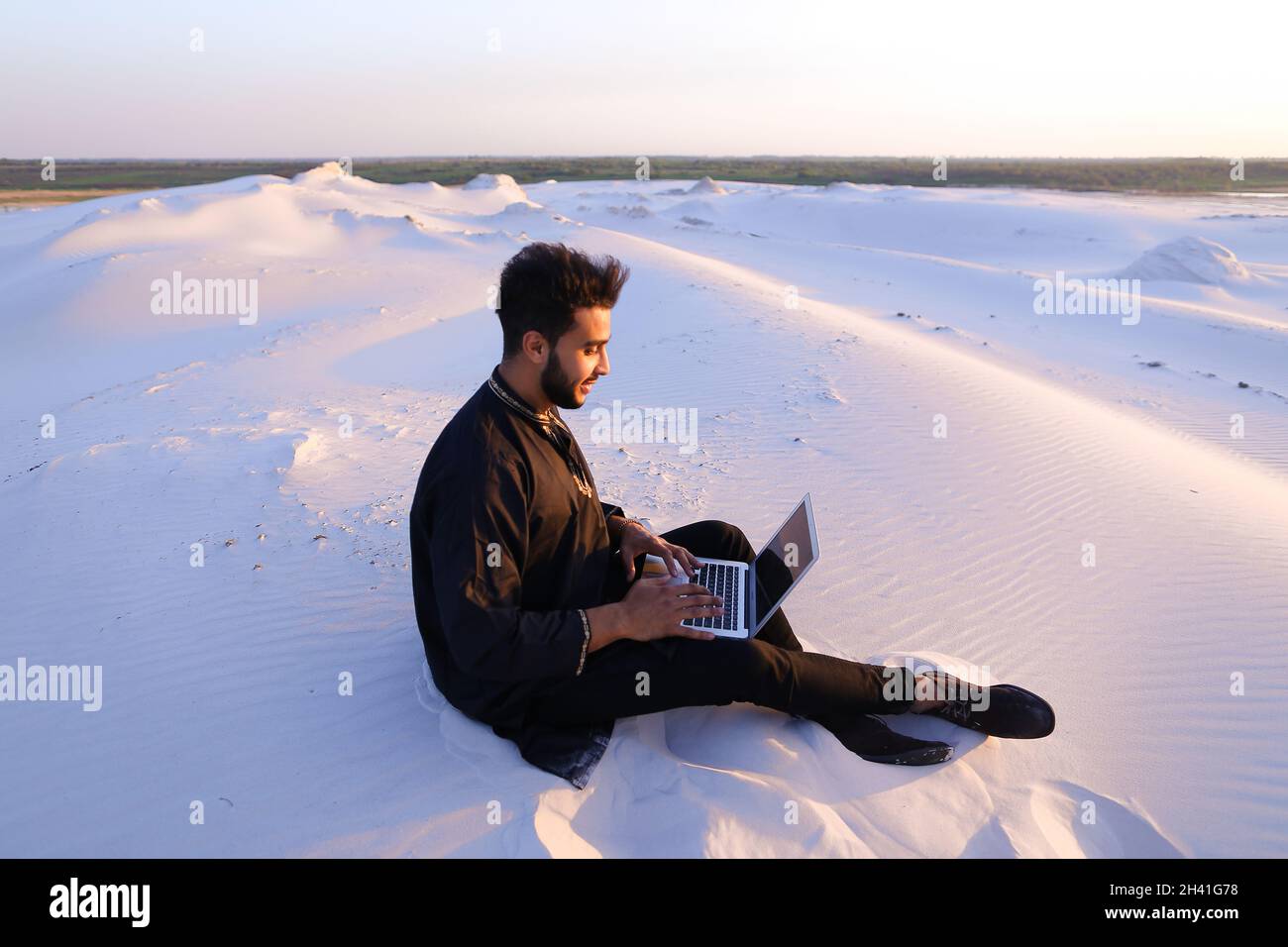 Handsome young Arab man writes on Internet using laptop and sits on ...