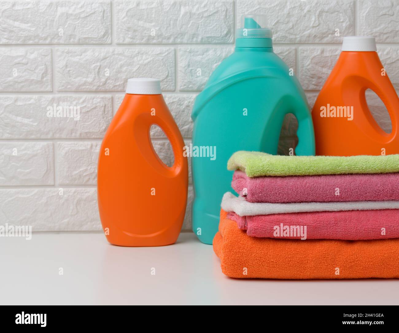 Plastic bottles with liquid detergent and folded towels on a white shelf. Bath interior Stock Photo