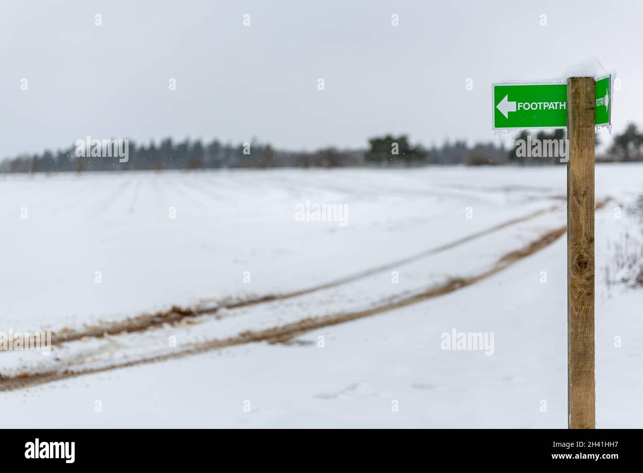 Public footpath sign pointing to the left with snow and icicles on it in rural British Countryside Stock Photo