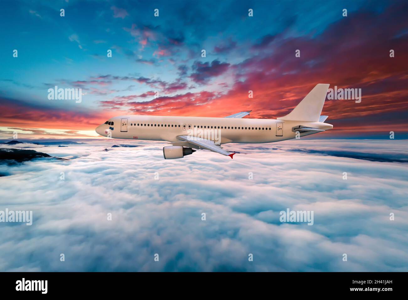 Airplane flying above the clouds at sunset Stock Photo