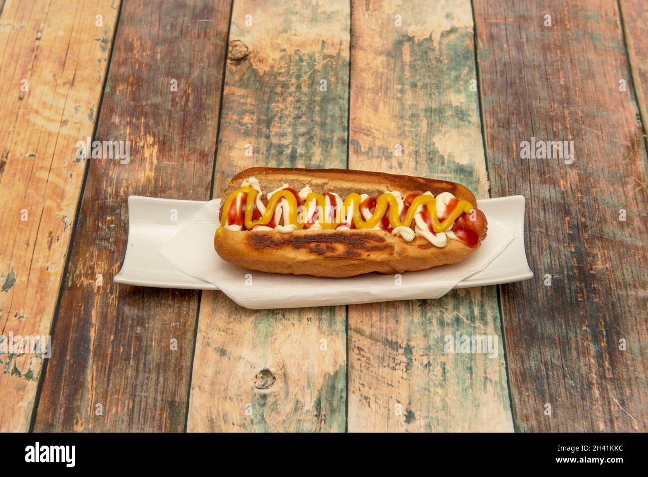 Delicious traditional hot dog with cooked sausage, mustard, ketchup and