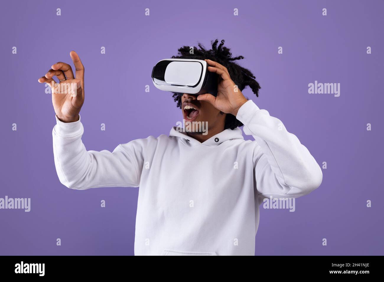 Amazed African American teen guy in VR headset using virtual reality ...