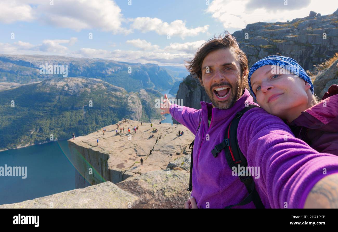 A cheerful couple in the summit of the Pulpit Rock (Preikestolen), one of the world's most spectacular viewing points. A plateau that rises 604 meters Stock Photo