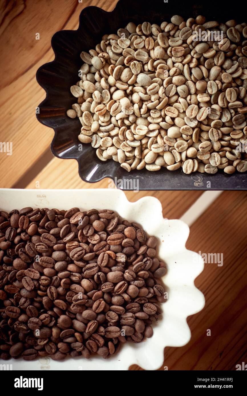 Bird-eye view of fragrant and aromatic raw and roasted coffee beans in containers nicely arranged on the table. Coffee, beverage, producing Stock Photo